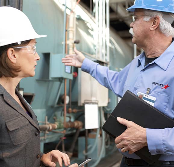 Two people wearing hardhats looking at equipment